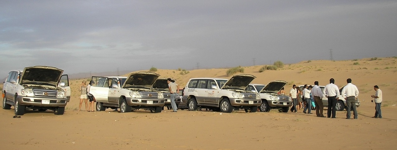 tourists ride jeeps in sand dunes dubai uae jun 2007